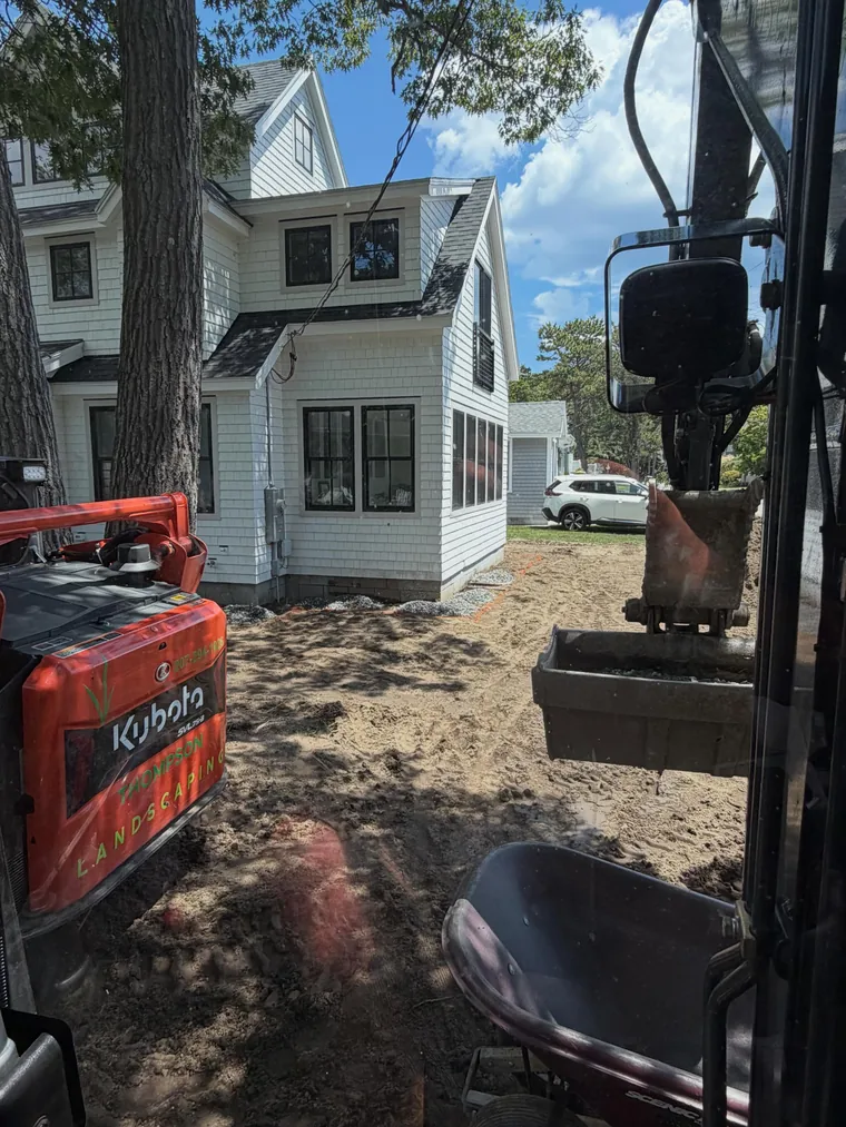 Landscaping equipment working beside a home and newly prepared ground.
