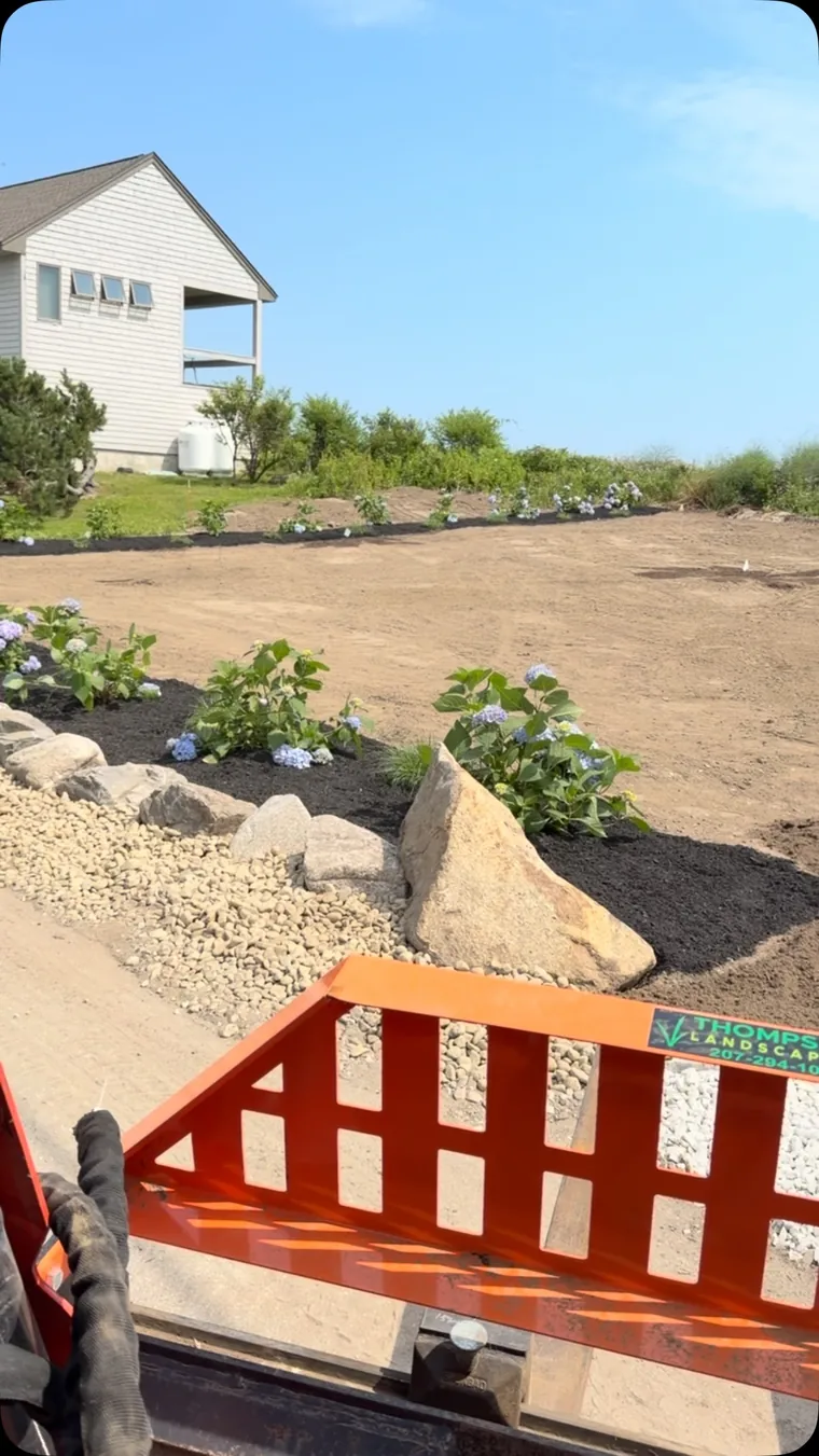 Garden beds and freshly prepared ground viewed from landscaping equipment.