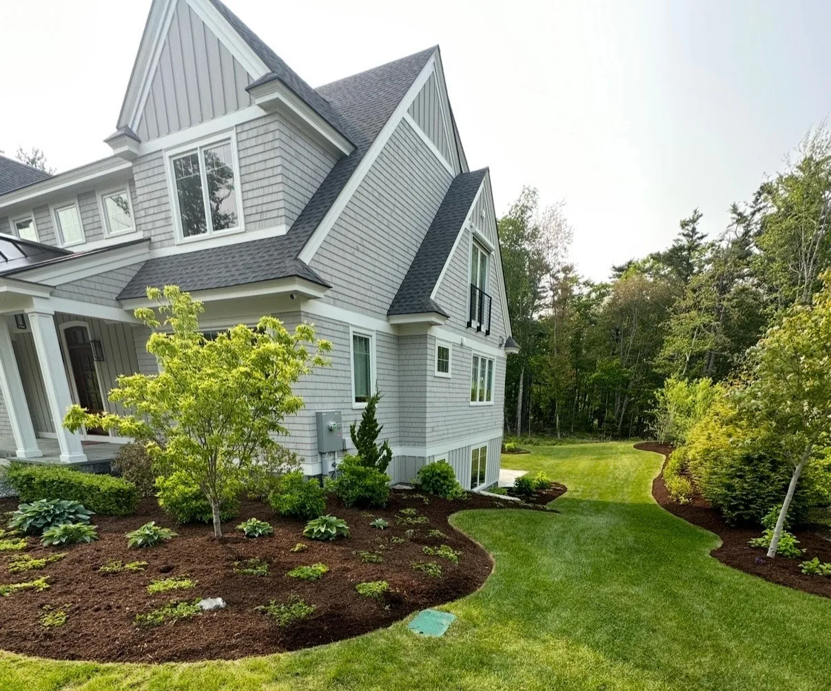 Fresh bark mulch around planting beds beside a gray home