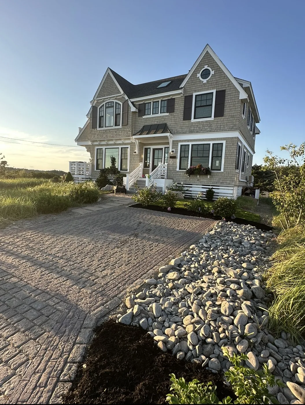 Paved driveway beside a landscaped home, with a stone border