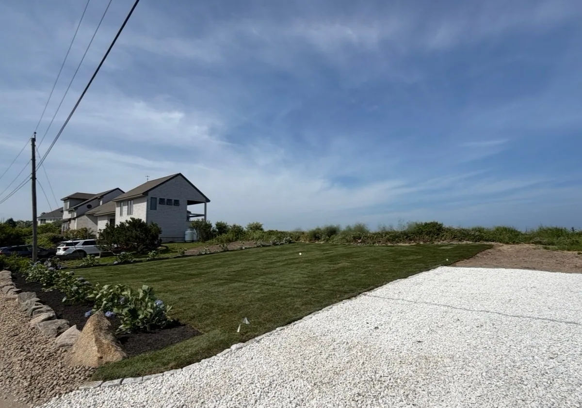 A green lawn, planted beds and gravel area after renovation.