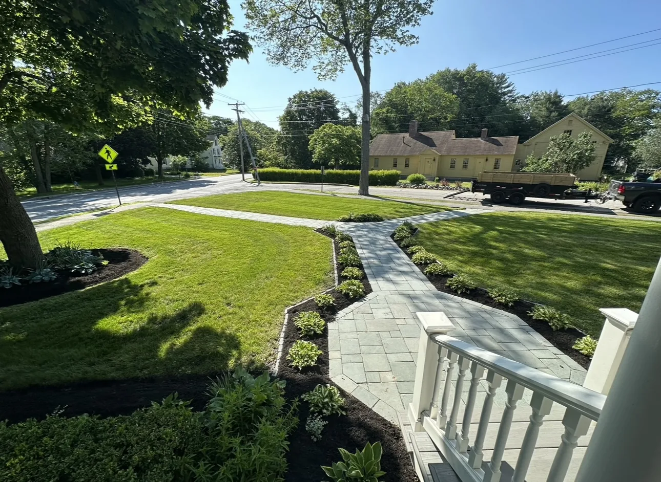 Stone front walkway with garden beds on both sides and a green lawn